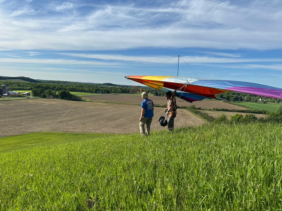 Pilot and glider on a grassy hill