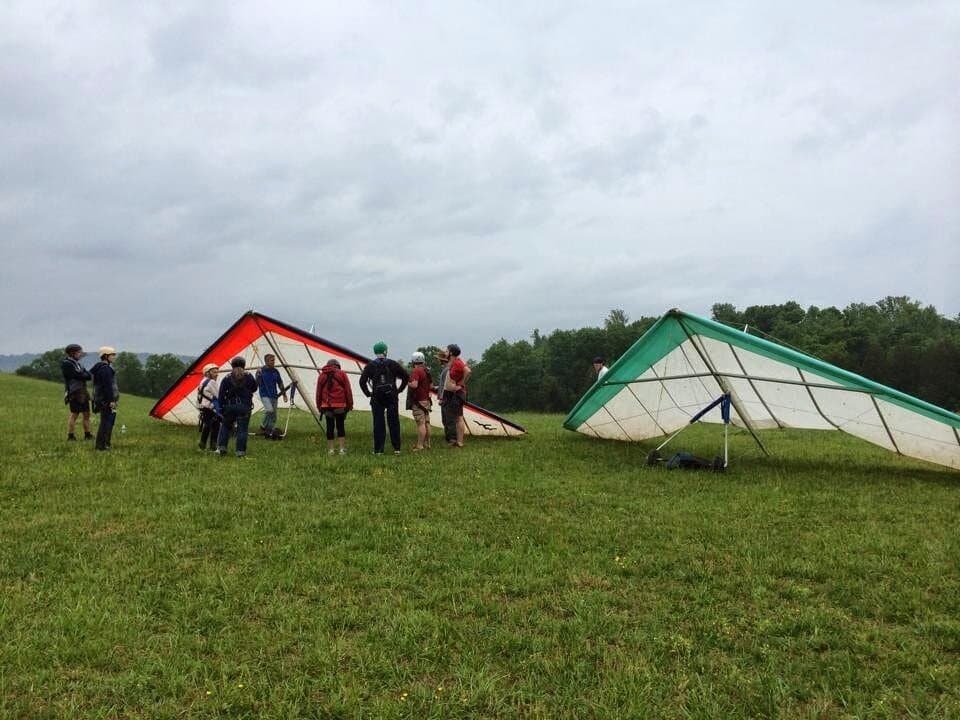 RAF pilots gathered beside two hang gliders on a grassy hill