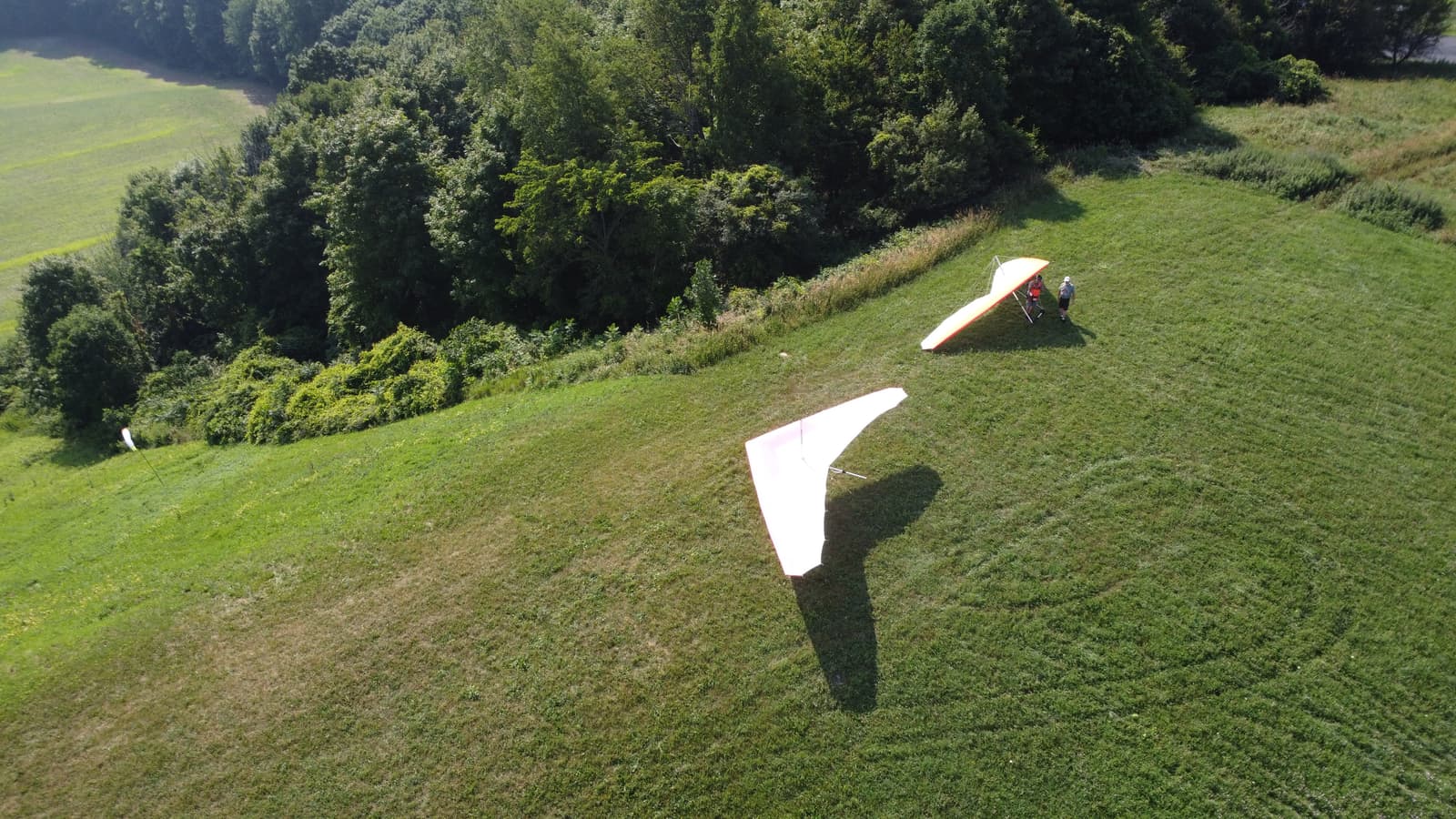 Hang-gliding equipment and people on a green training hill